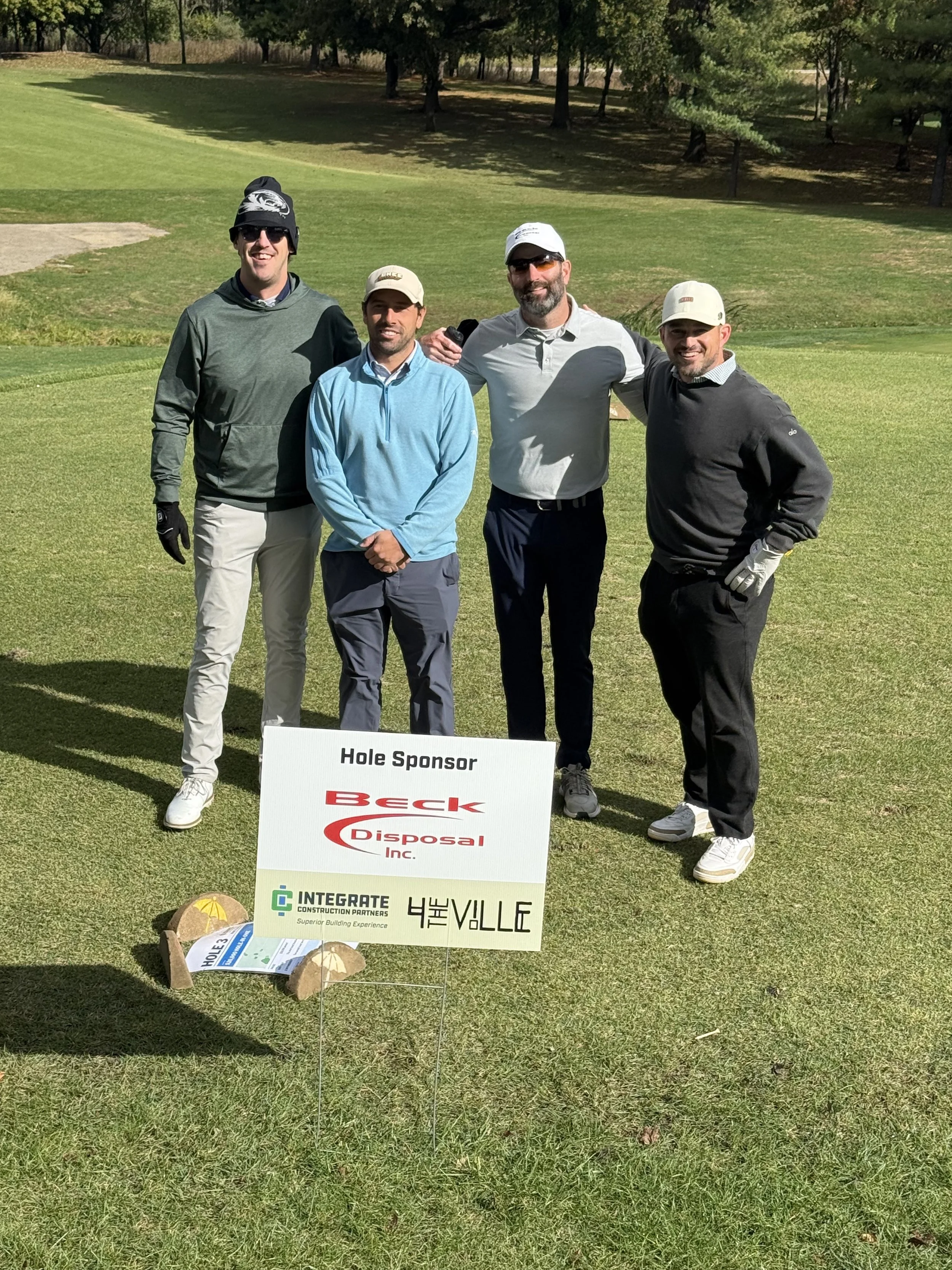 Golf outing participants beside a Beck Disposal hole sponsor sign