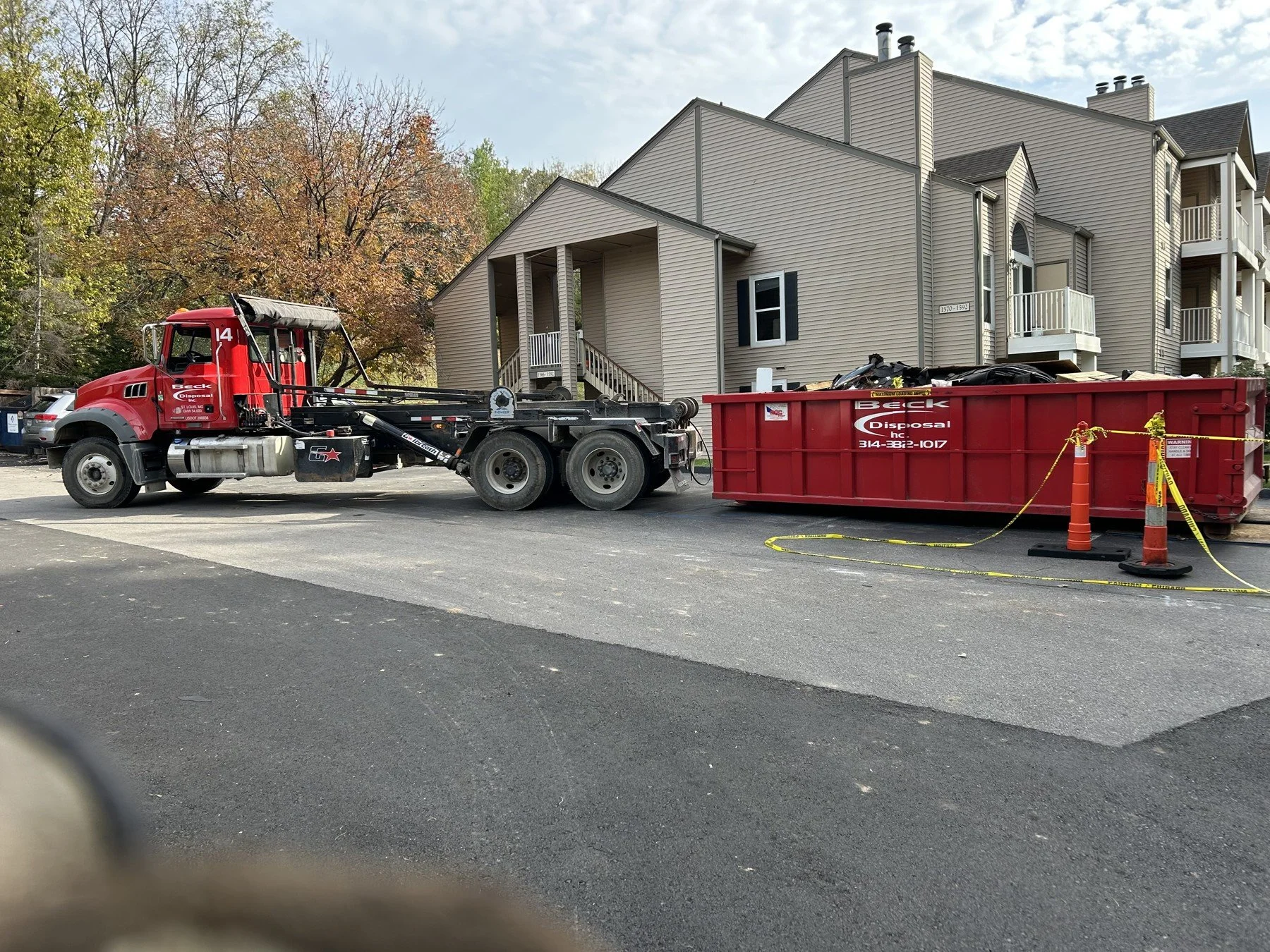Beck roll-off truck and container beside a multifamily residential building