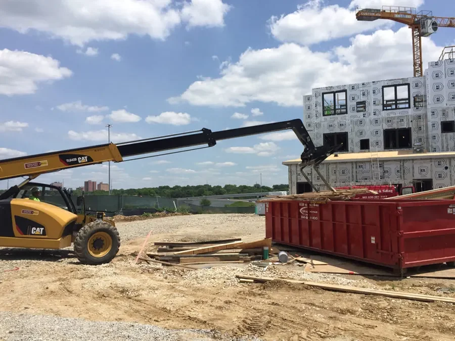 Beck container beside a telehandler and a building under construction