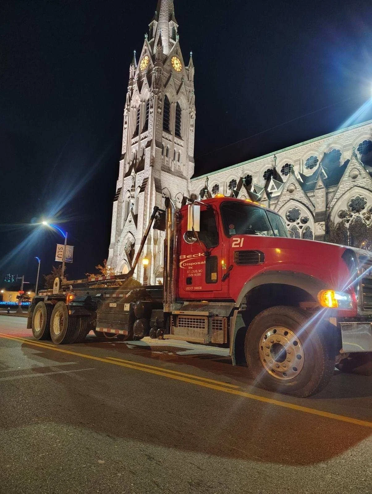Beck roll-off truck parked beside an illuminated church at night
