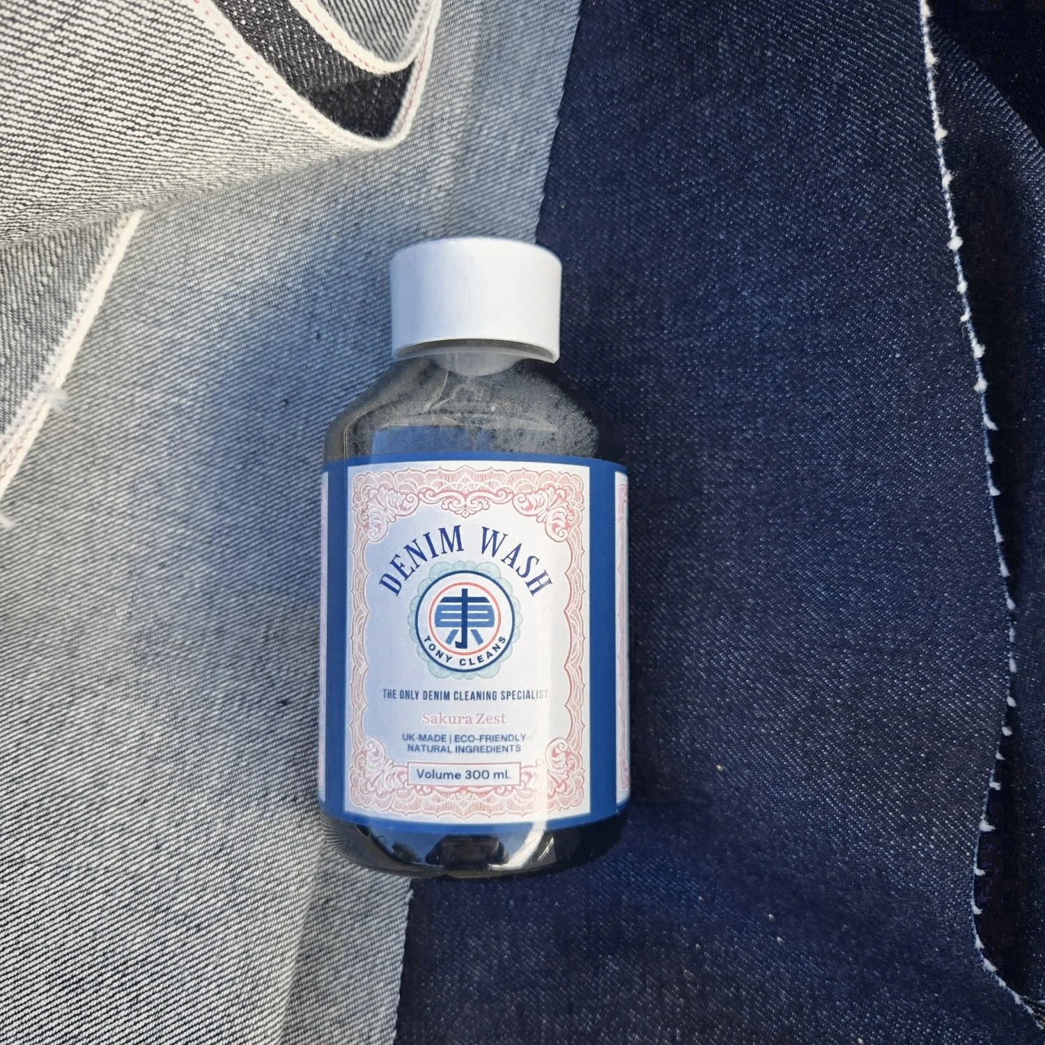 Tony Cleans Denim Wash bottle resting on raw and washed denim