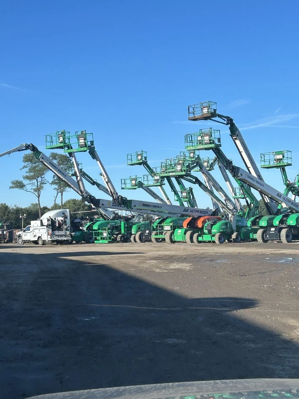 Fleet of boom lifts raised and staged on a job site