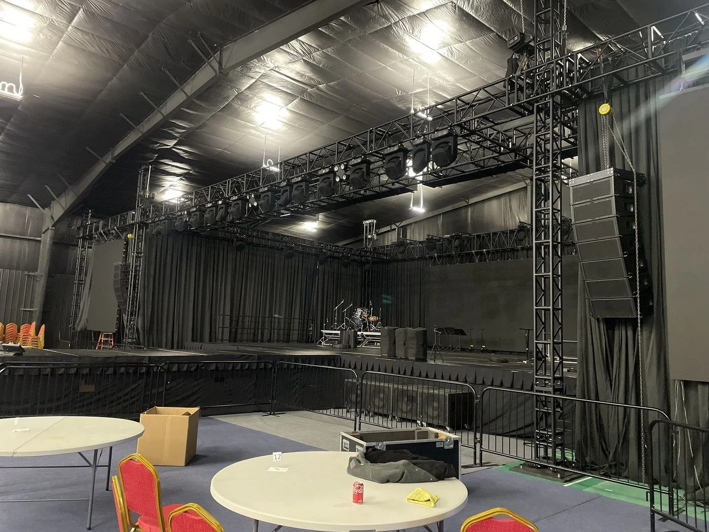 Black truss rig with moving lights and a flown line array over a stage
