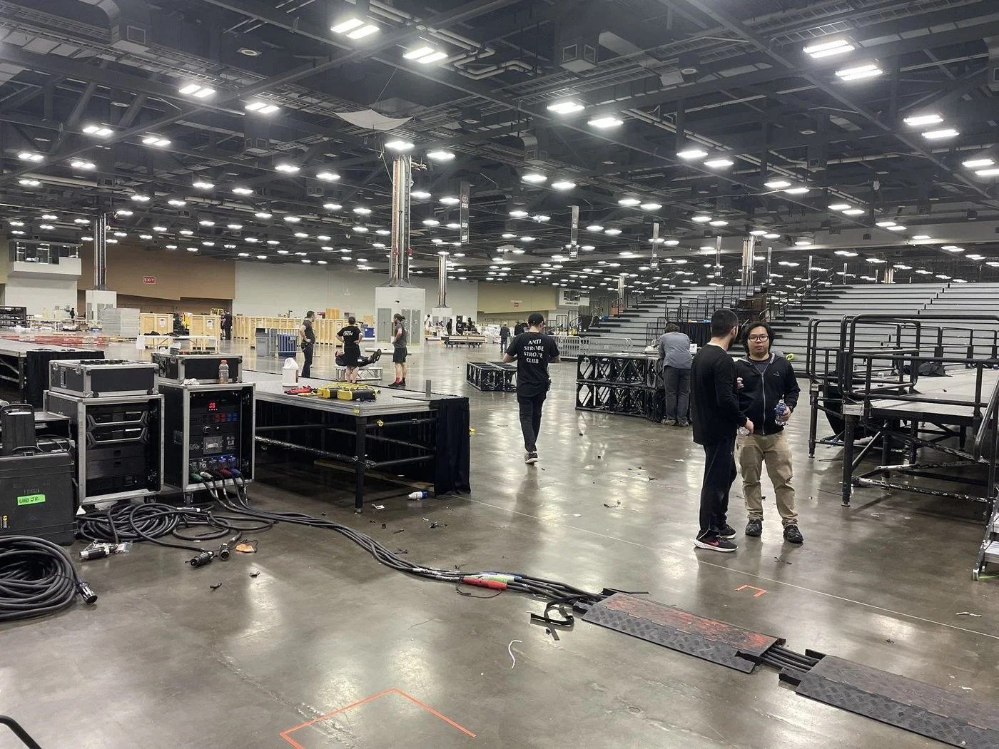 Exhibit hall load-in with staging, power distribution and cable runs laid out by the crew
