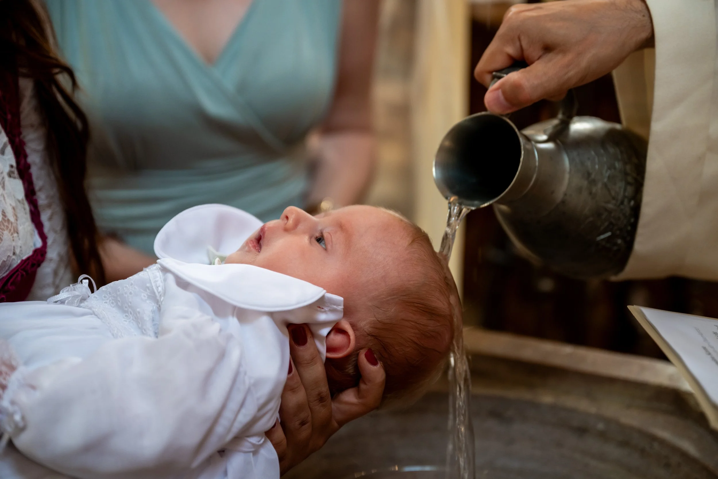 Taufwasser wird über das Köpfchen gegossen