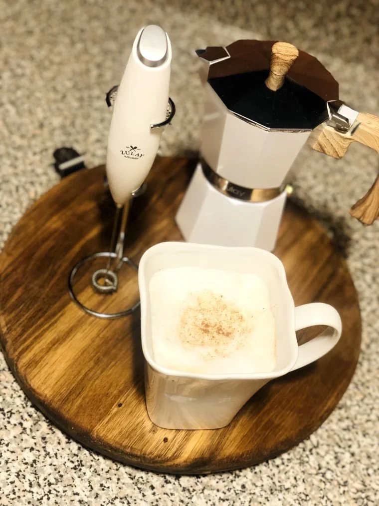 A frothed cappuccino with nutmeg, the frother and the moka pot
