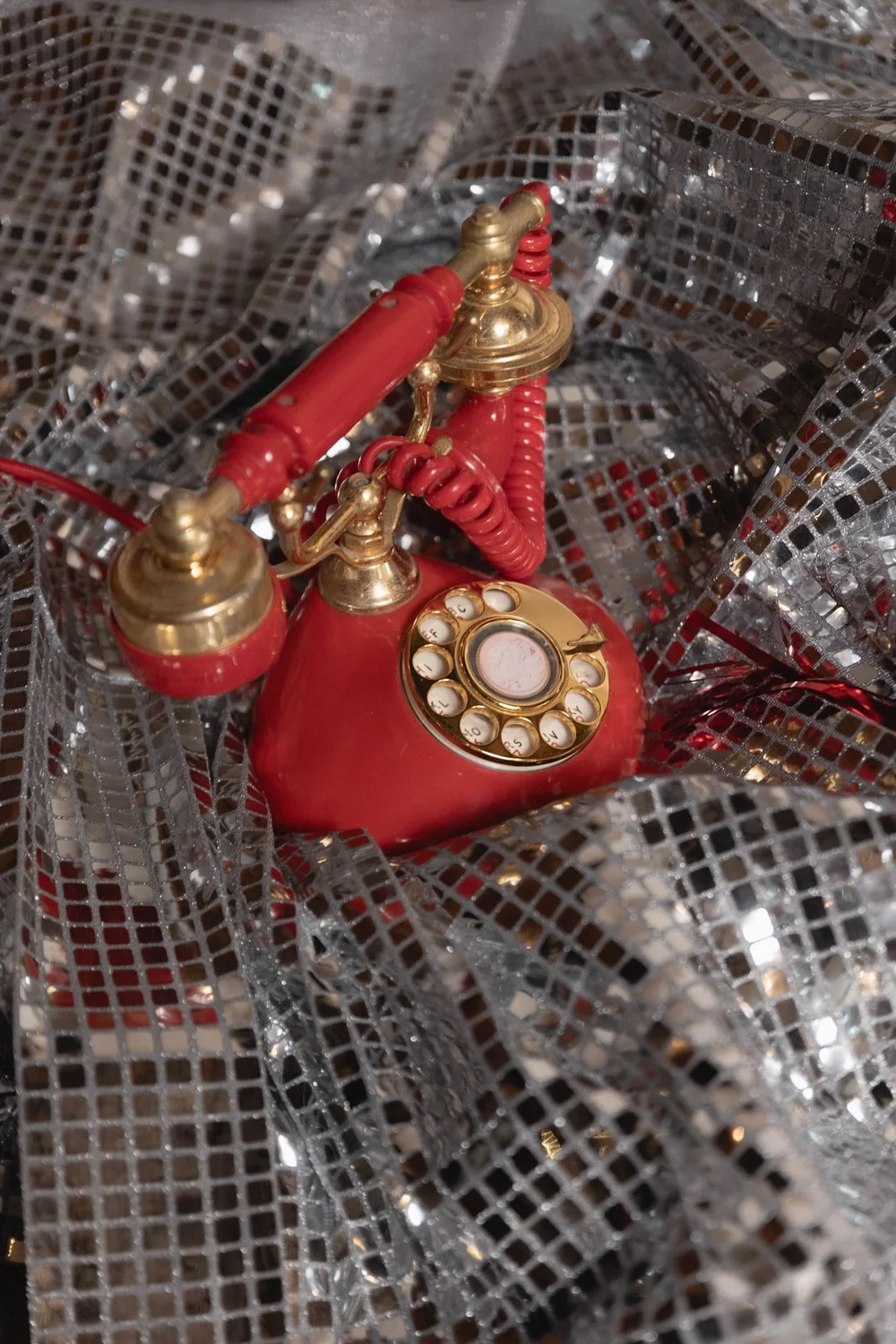 Vintage red rotary phone on silver sequins