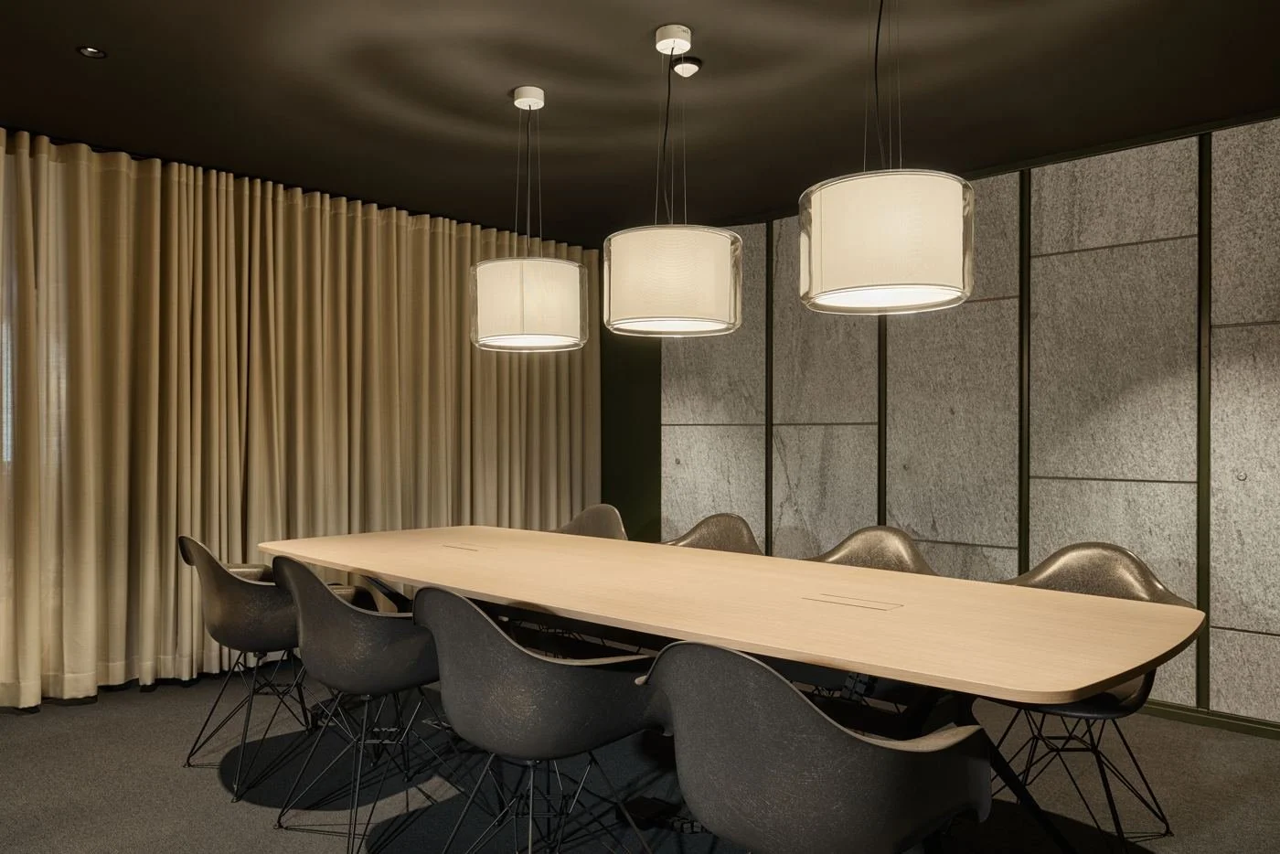 A private meeting room with a long oak table under three pendant lights