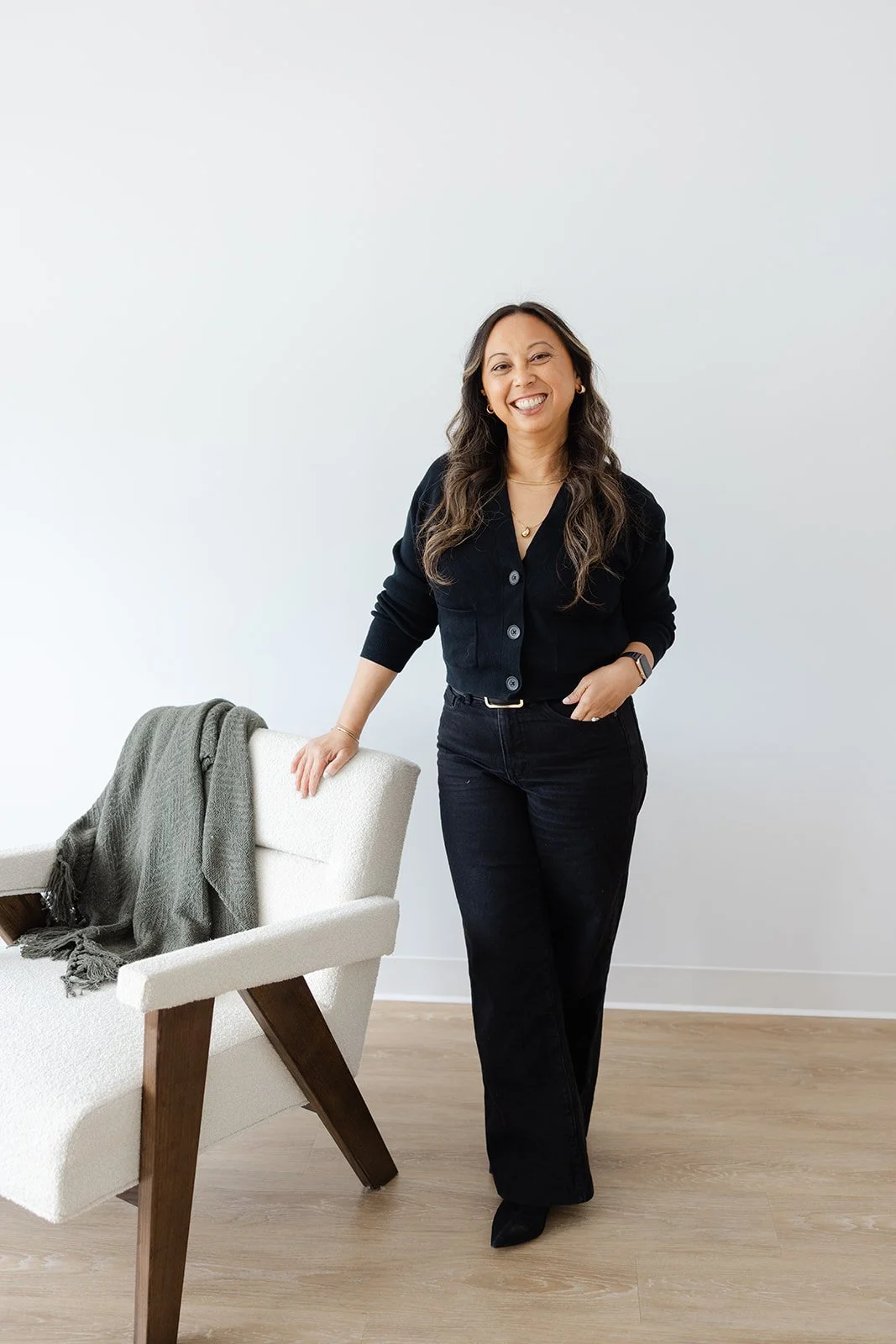 A branding portrait of a woman leaning on a cream boucle accent chair