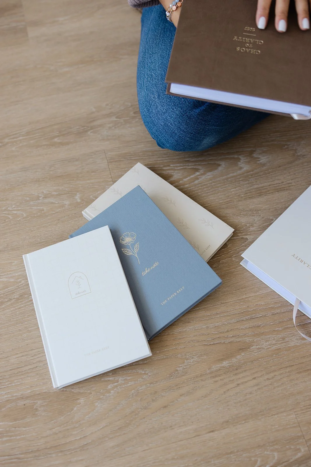 Notebooks and planners laid out on the wood floor for a flat lay product shoot