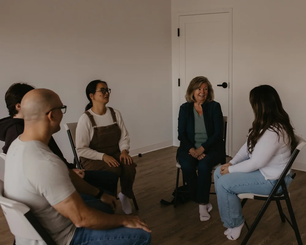 A group seated on chairs in a circle, sharing in conversation