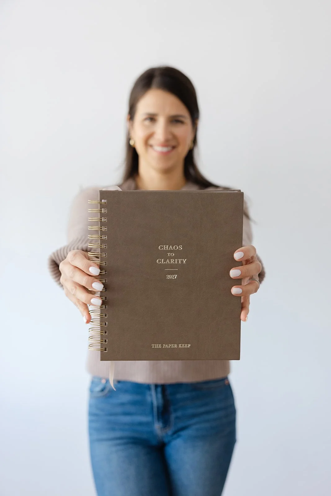 A woman holding a planner toward the camera for a product shoot