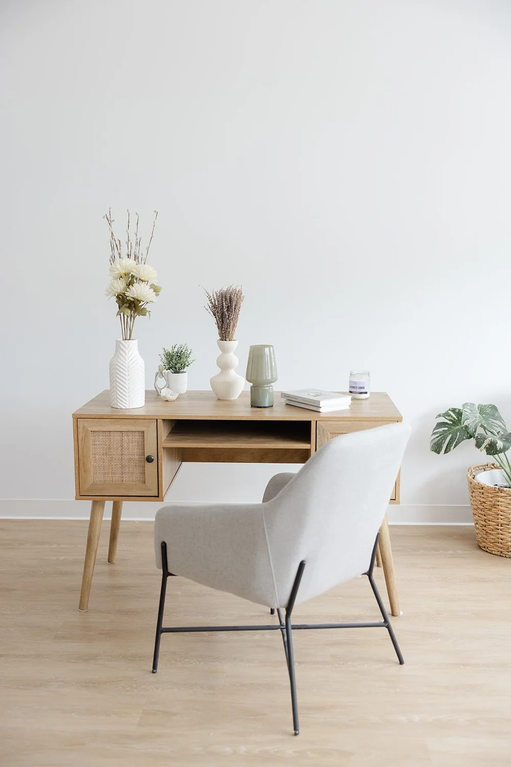 The styled writing desk with vases, a lamp and a grey accent chair