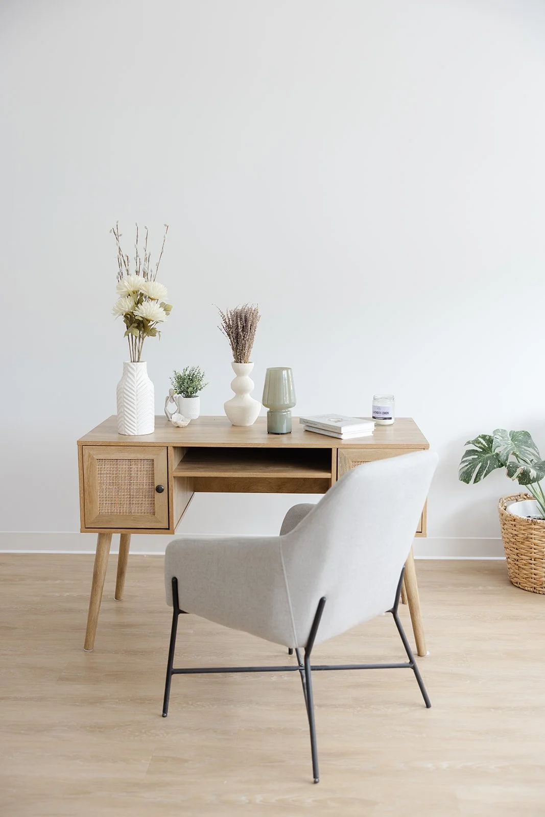 The styled writing desk with vases, a lamp and a grey accent chair
