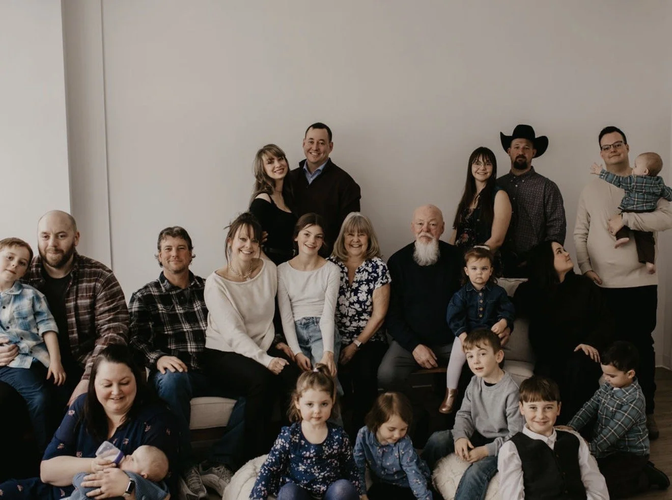 A large multi-generational family portrait against the white studio wall