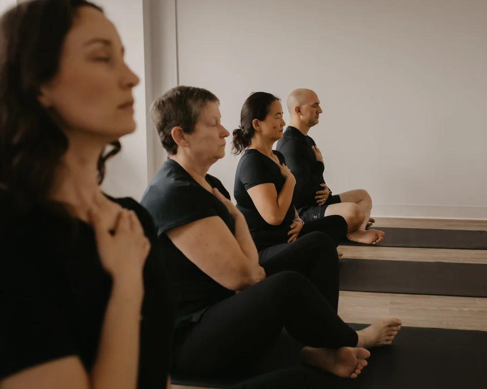 Participants seated on mats with hands on their hearts during breathwork