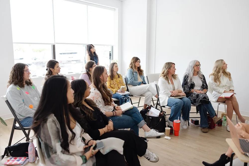 A room of guests seated together, listening during a community event