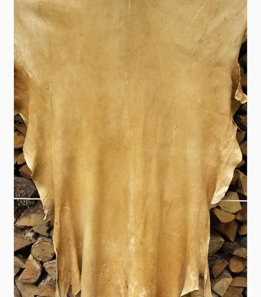 Golden-tanned hide displayed in front of stacked firewood