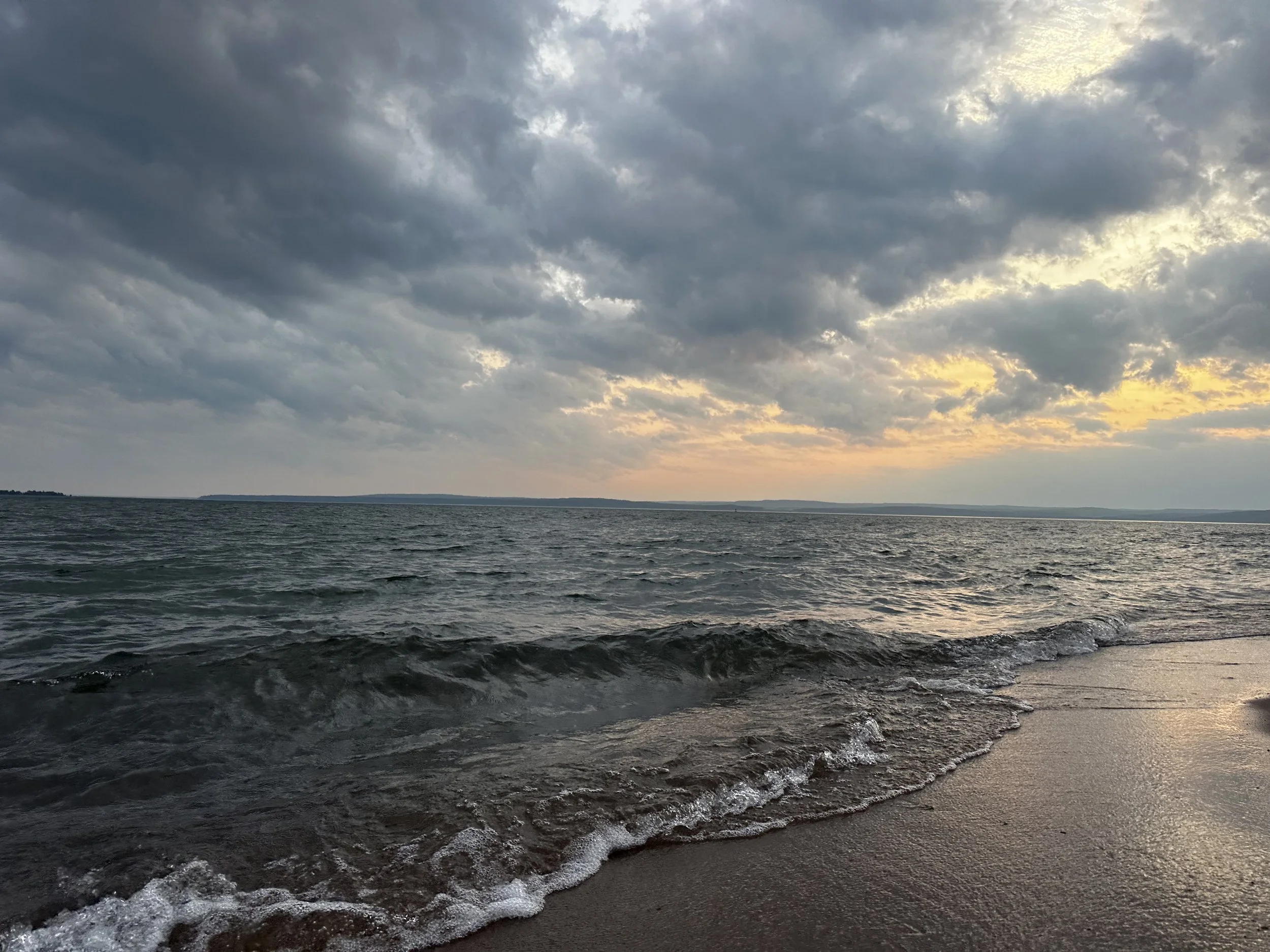 Lake Superior waves meeting Madeline Island’s sandy shore beneath a golden evening sky