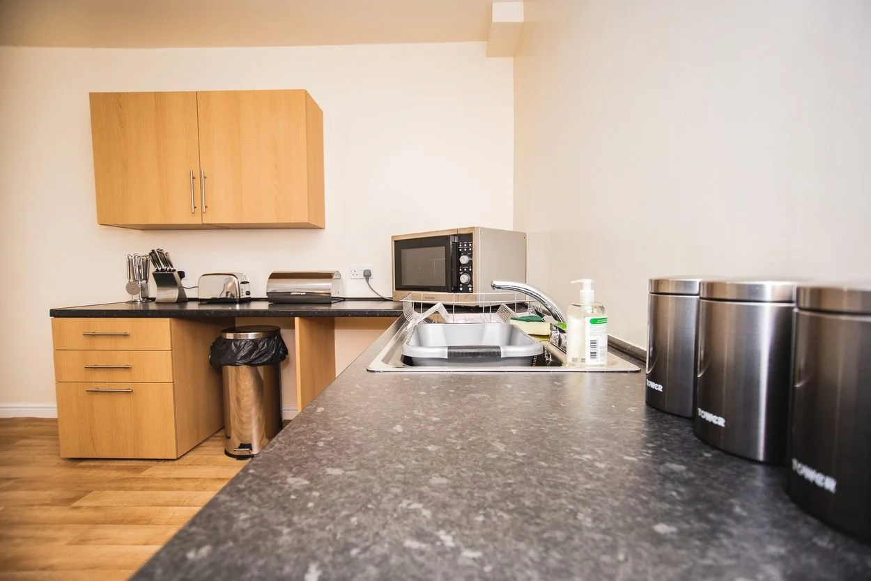 A modern kitchen with wooden cupboards and a dark worktop