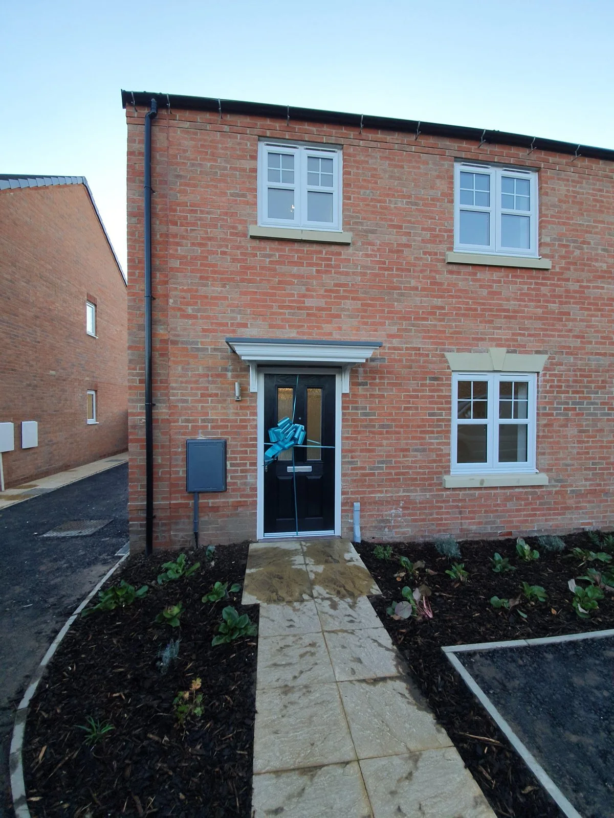 The front of the red brick home with a path and planted borders