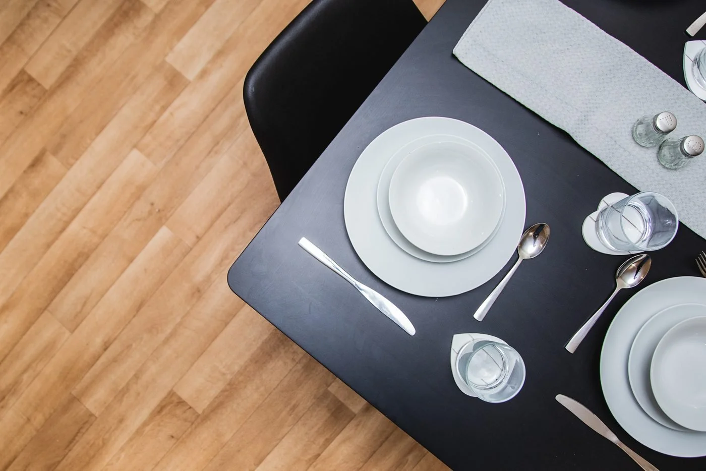 A dining table set with plates, cutlery and glasses