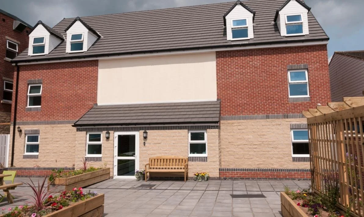 Outside the home in Laughton en le Morthen, a three-storey brick building with a paved courtyard