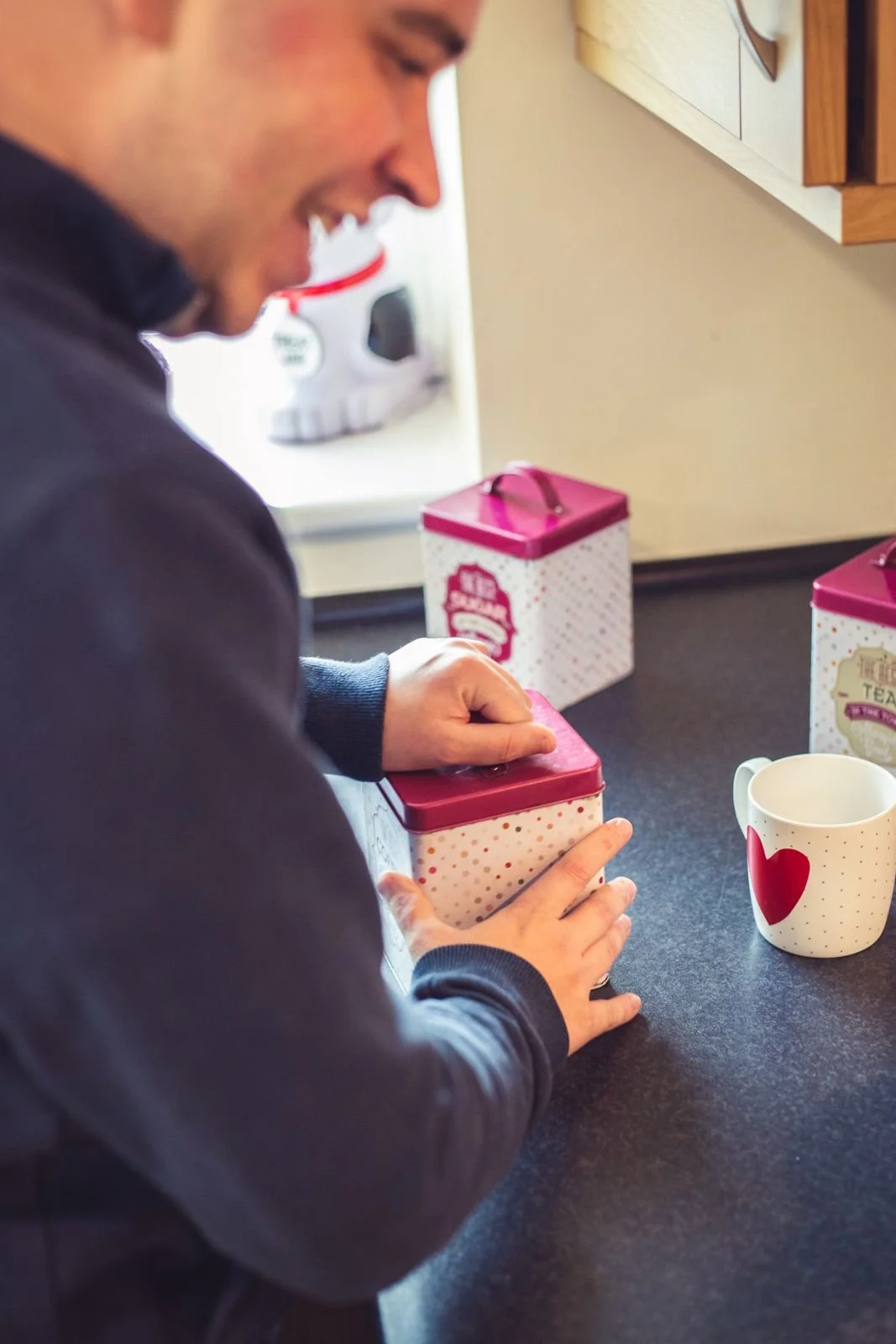A man smiling as he makes a cup of tea in his kitchen