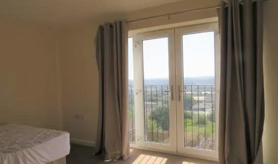 A bedroom with French doors and a view over the city
