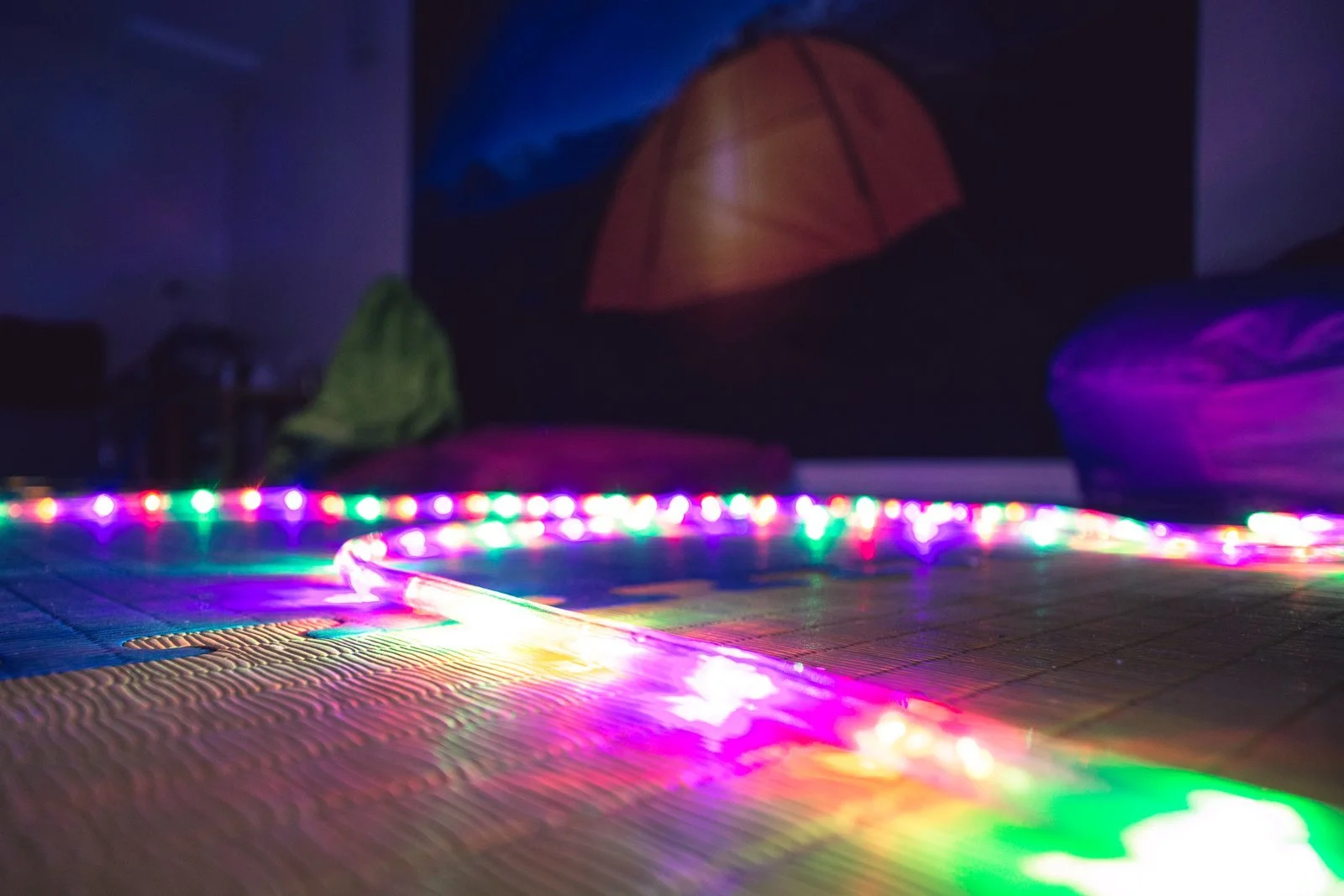A sensory room with colourful light strips, beanbags and soft flooring