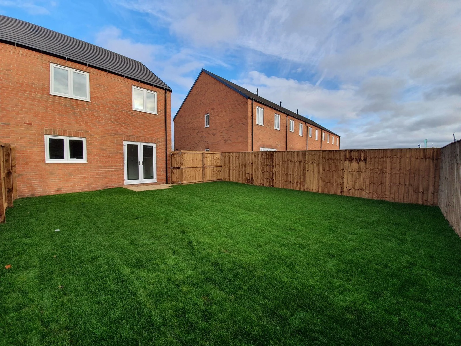 A large lawned rear garden with fencing