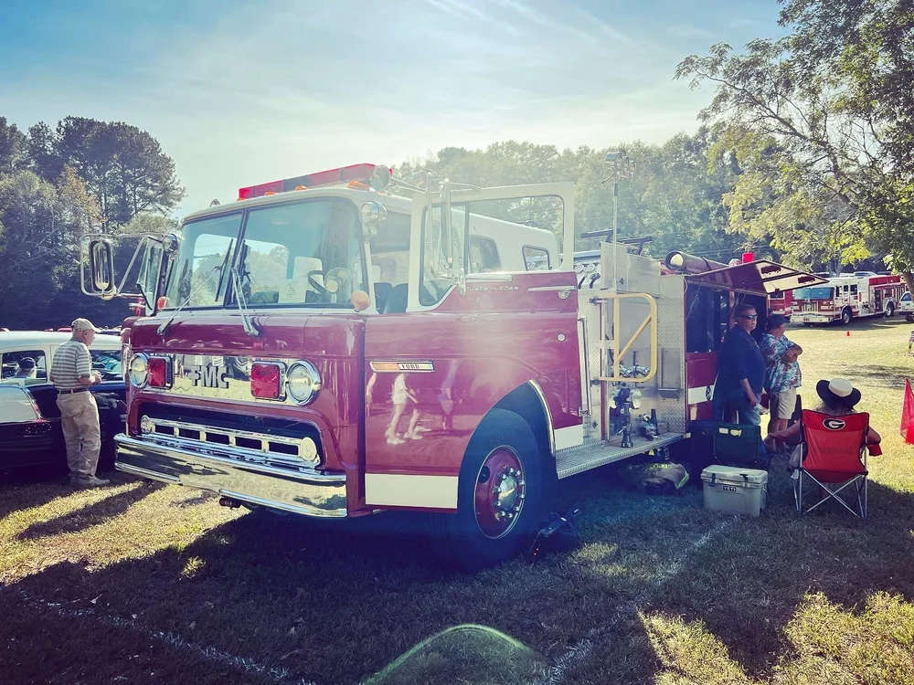 Engine 706 parked on the grass with visitors at a Watkinsville car show.