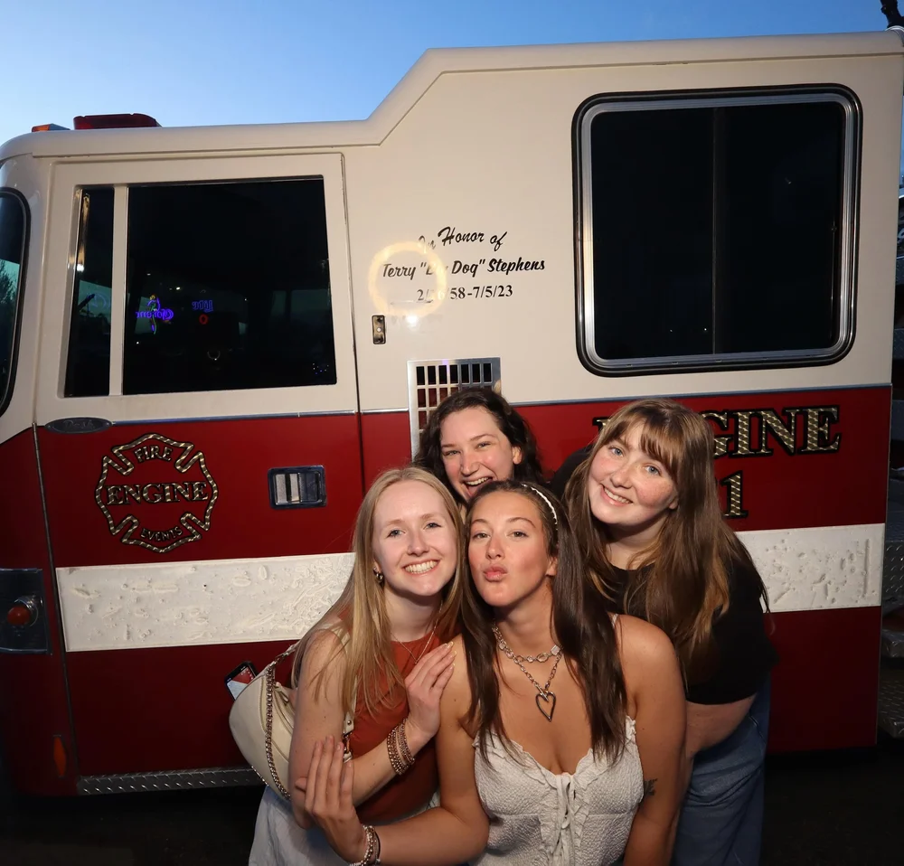 Four guests smiling beside the red-and-white Fire Engine Events truck at Dos Palmas.