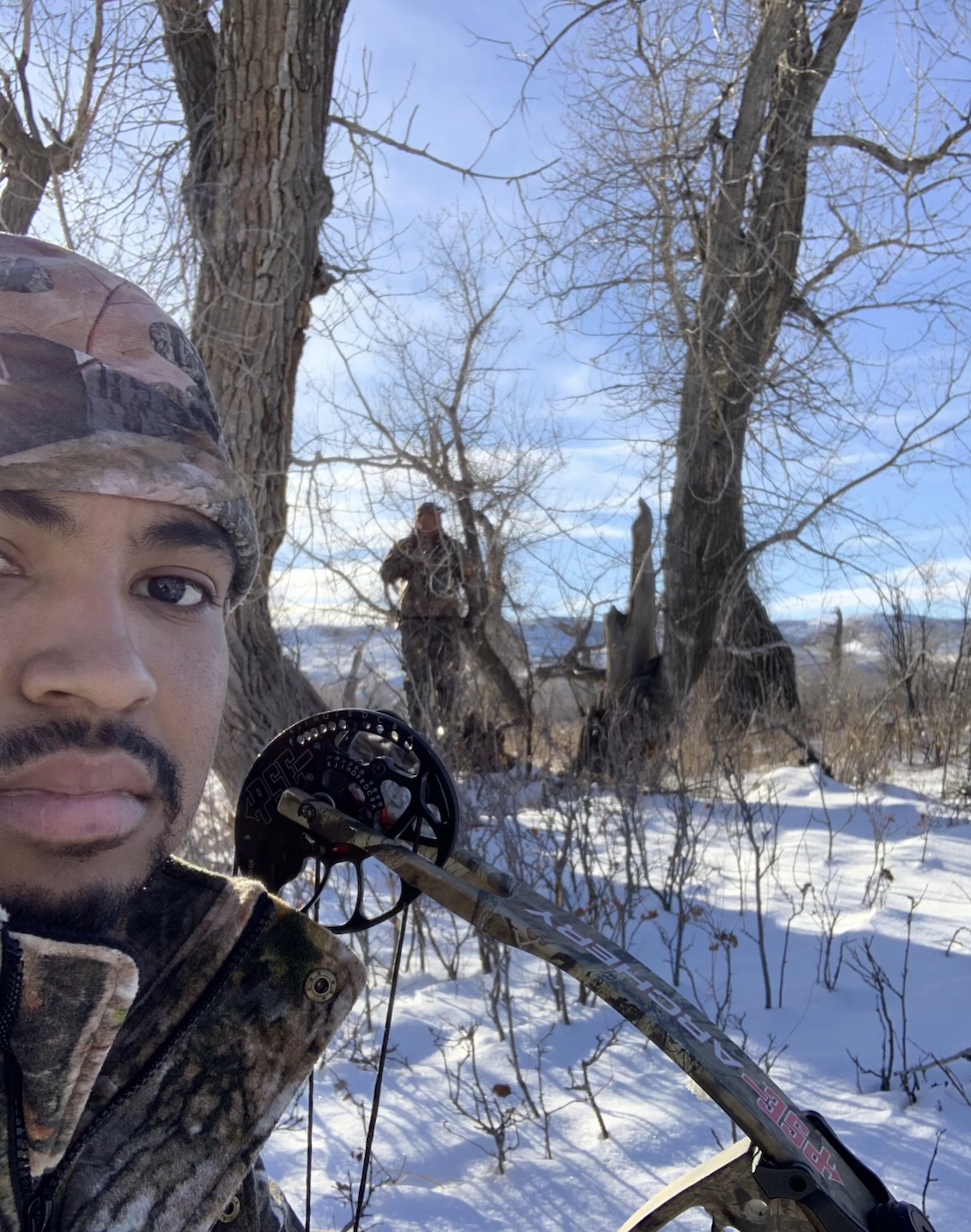 Ali outdoors with a bow in a snowy woodland