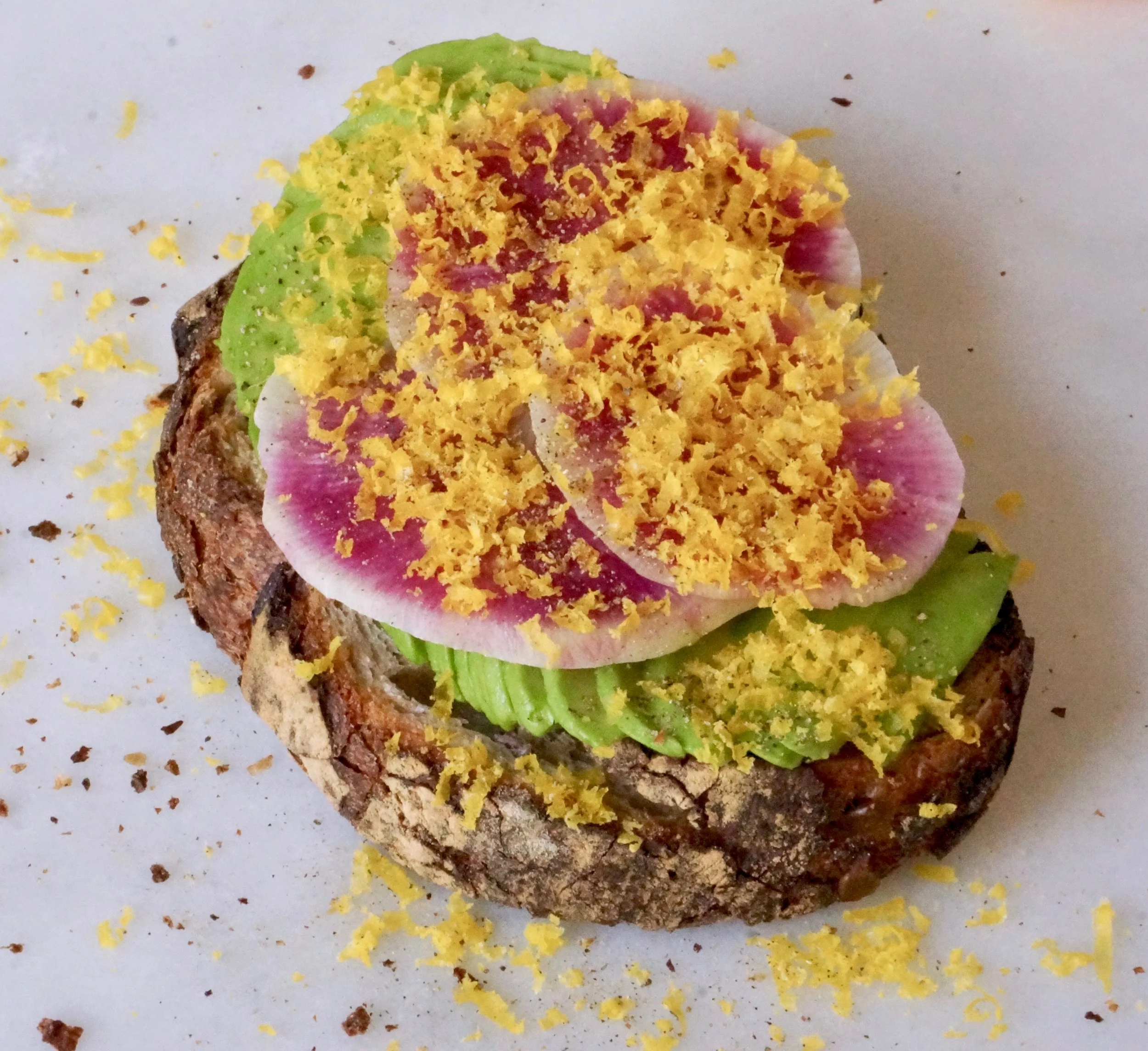 sourdough toast with avocado, watermelon radish and grated cured egg yolk