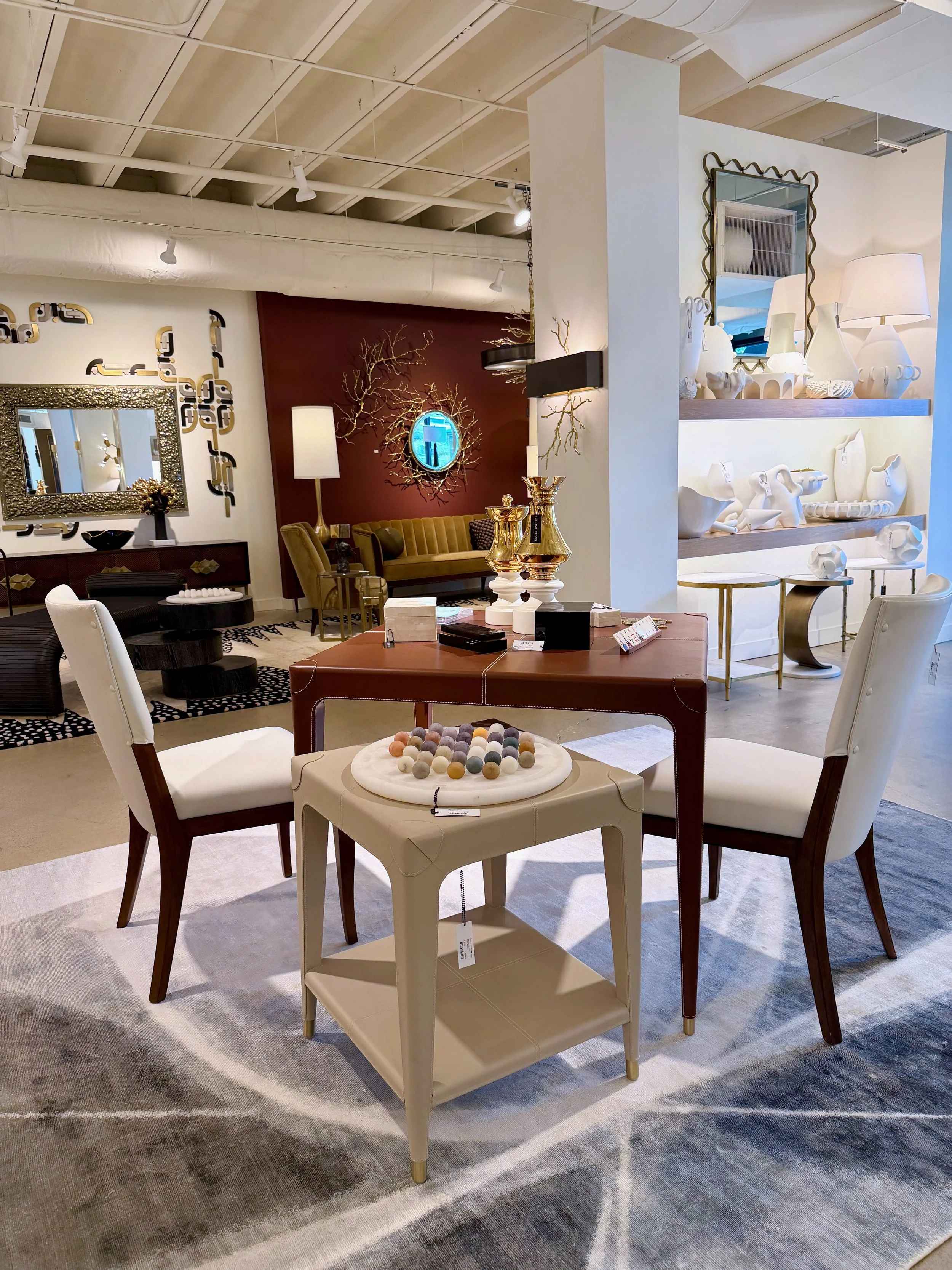A leather game table set with mahjong tiles and a smaller table to the side with a white marble game board holding multicolored stone game pieces.