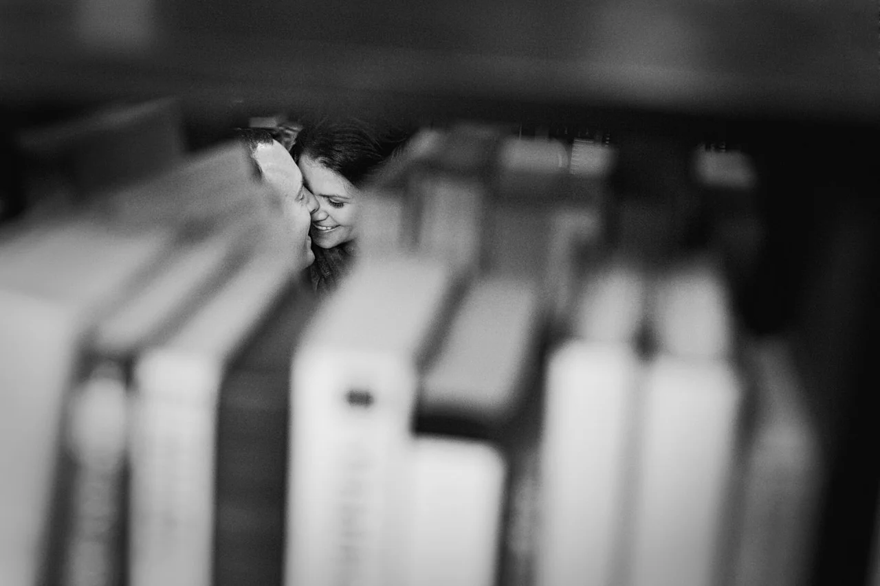 Black and white shot ofngaged couple snuggling in bookstore - Maria Vicencio Photography Engagement Session