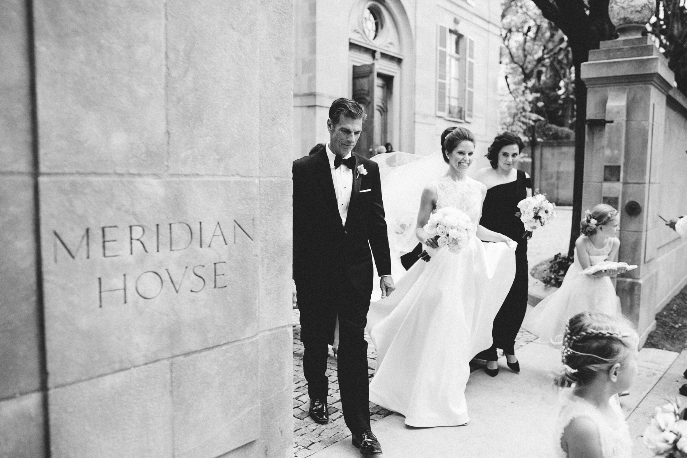 Black and white shot of bride and her family and bridal party walking to the ceremony at Meridian House in DC - Maria Vicencio Photography Weddings
