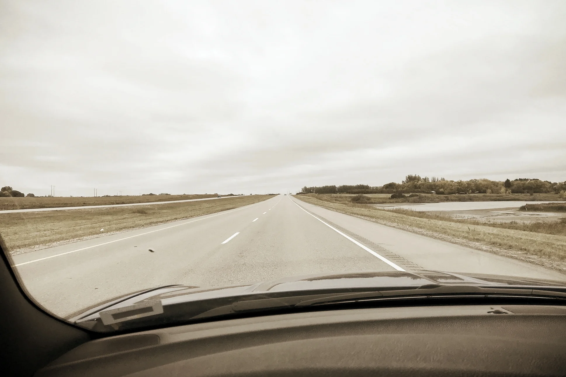 view across the dashboard through a windshield of a highway on a grey day