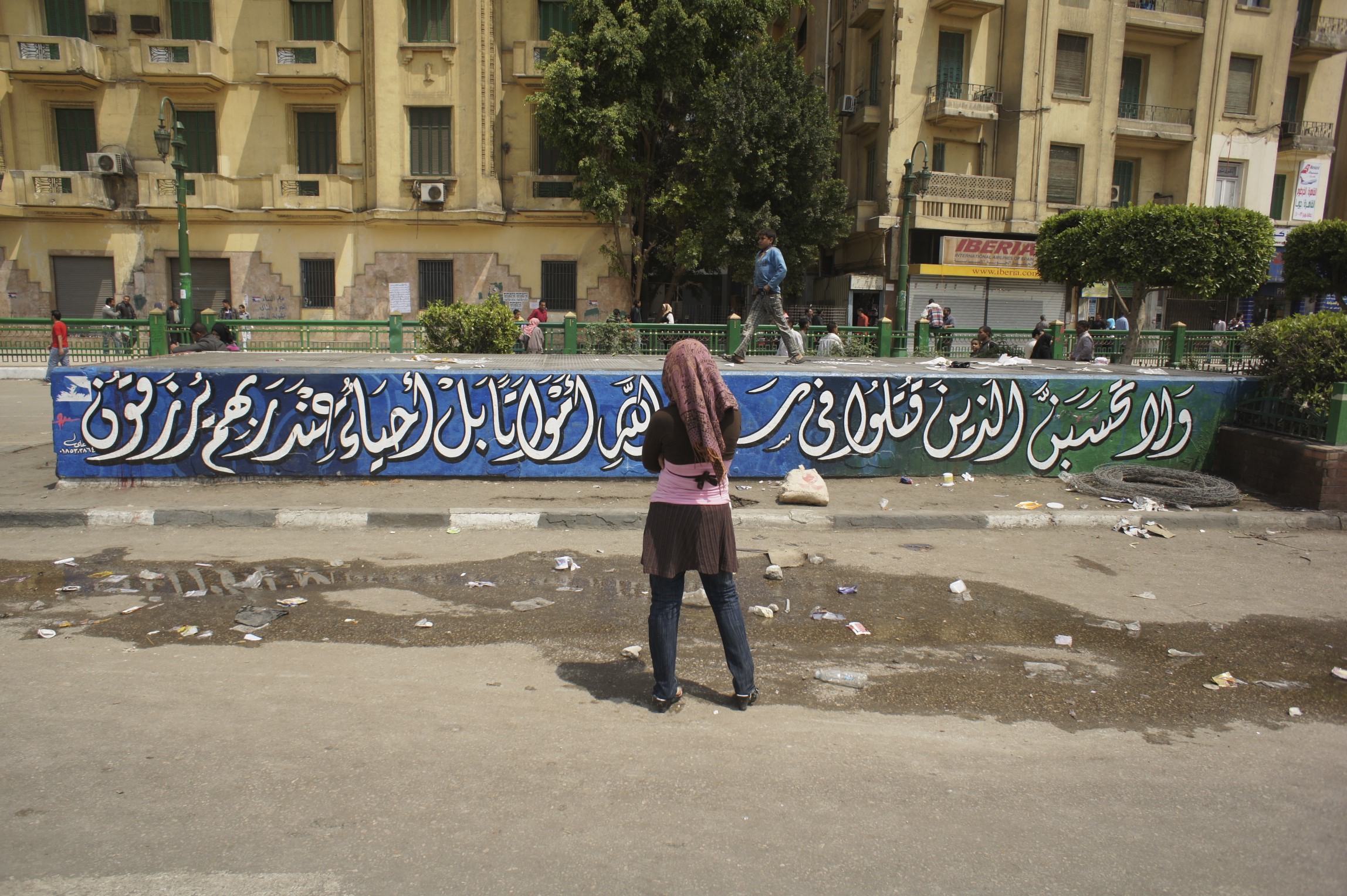 A woman looks at a graffiti of a quote from the Quran, Tahrir Square, November 2011. Photo by Issandr El Amrani.