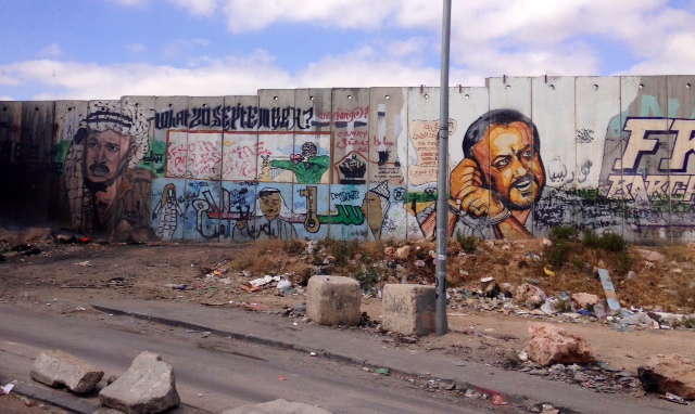 Approaching the Qalandiya Crossing into Jerusalem (the only entrance for Palestinians on foot), graffiti of Yasser Arafat and jailed leader Marwan Barghouti