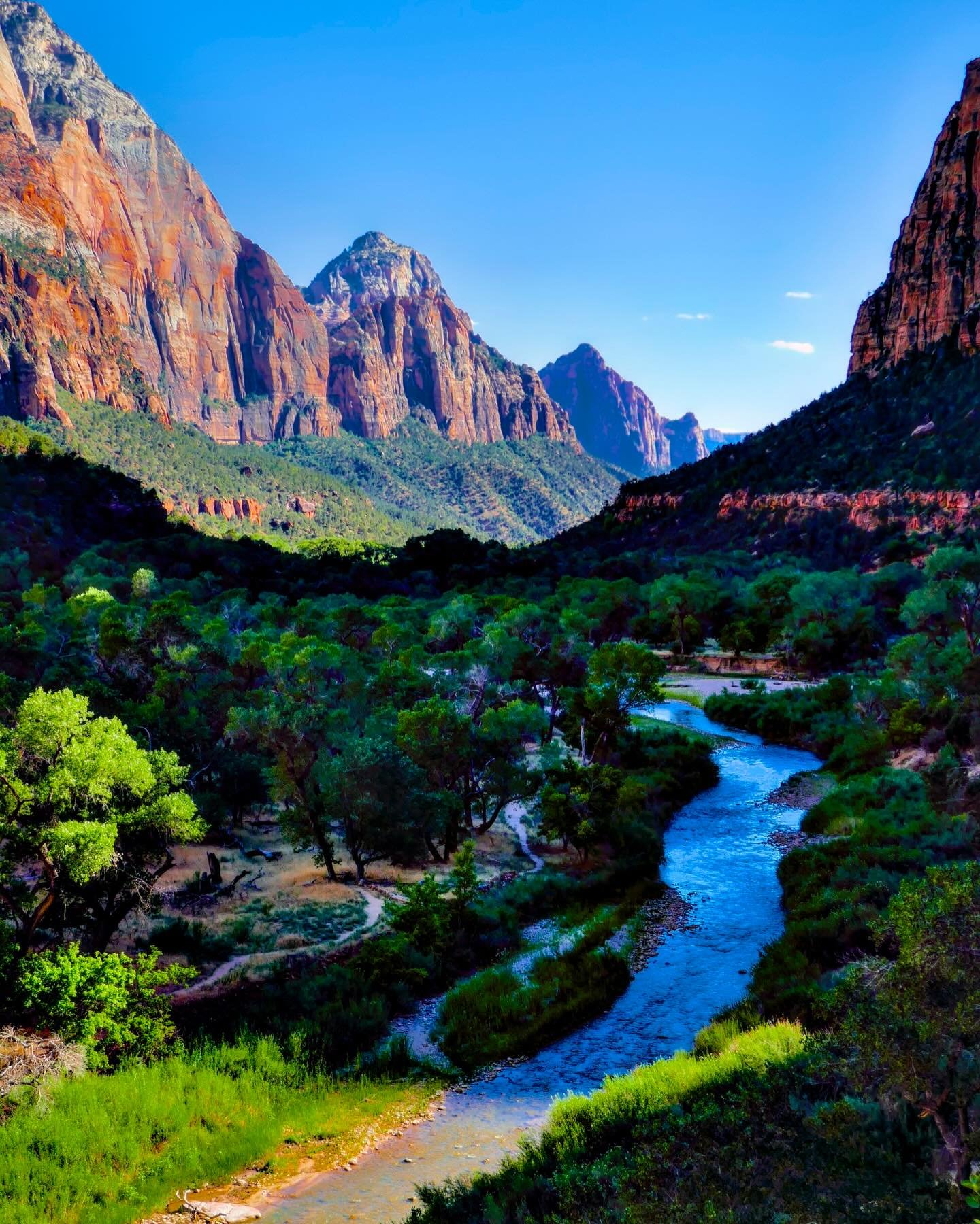 Description&rdquo;Zion Breeze&rdquo; &copy; 2025 Skip Hunt

A serene river meanders through a lush valley, flanked by towering, rugged mountains under a clear blue sky. Sunlight casts vibrant hues across the landscape, highlighting the mix of green v