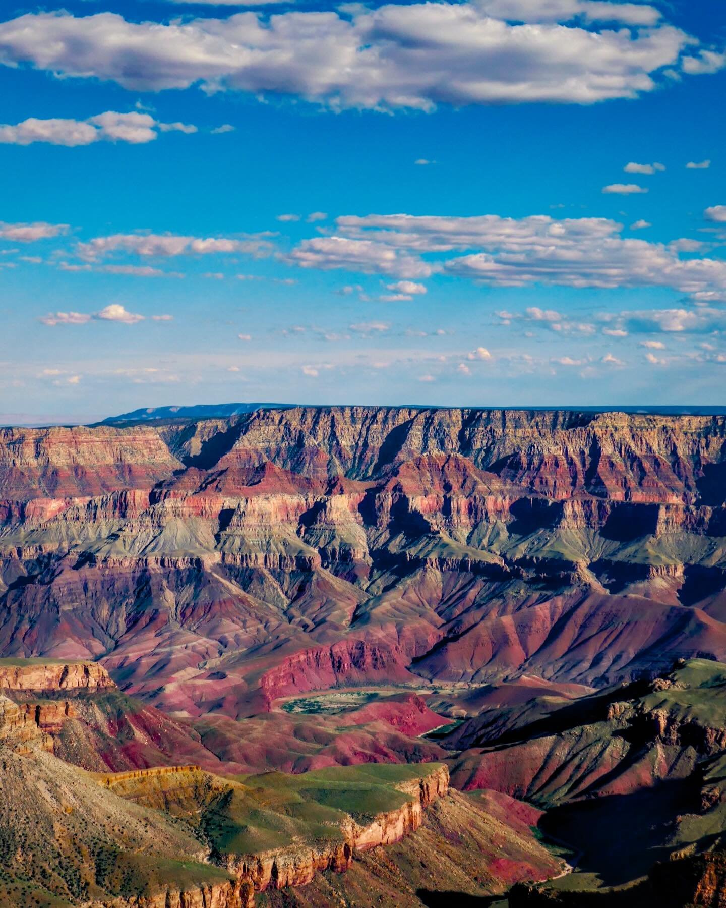 &ldquo;Singing Bowl&rdquo; &copy; 2025 Skip Hunt

Vast layers of reds, purples, and browns form the majestic rock formations of the Grand Canyon under a bright blue sky. Fluffy white clouds drift gently, adding contrast to the vivid colors of the lan