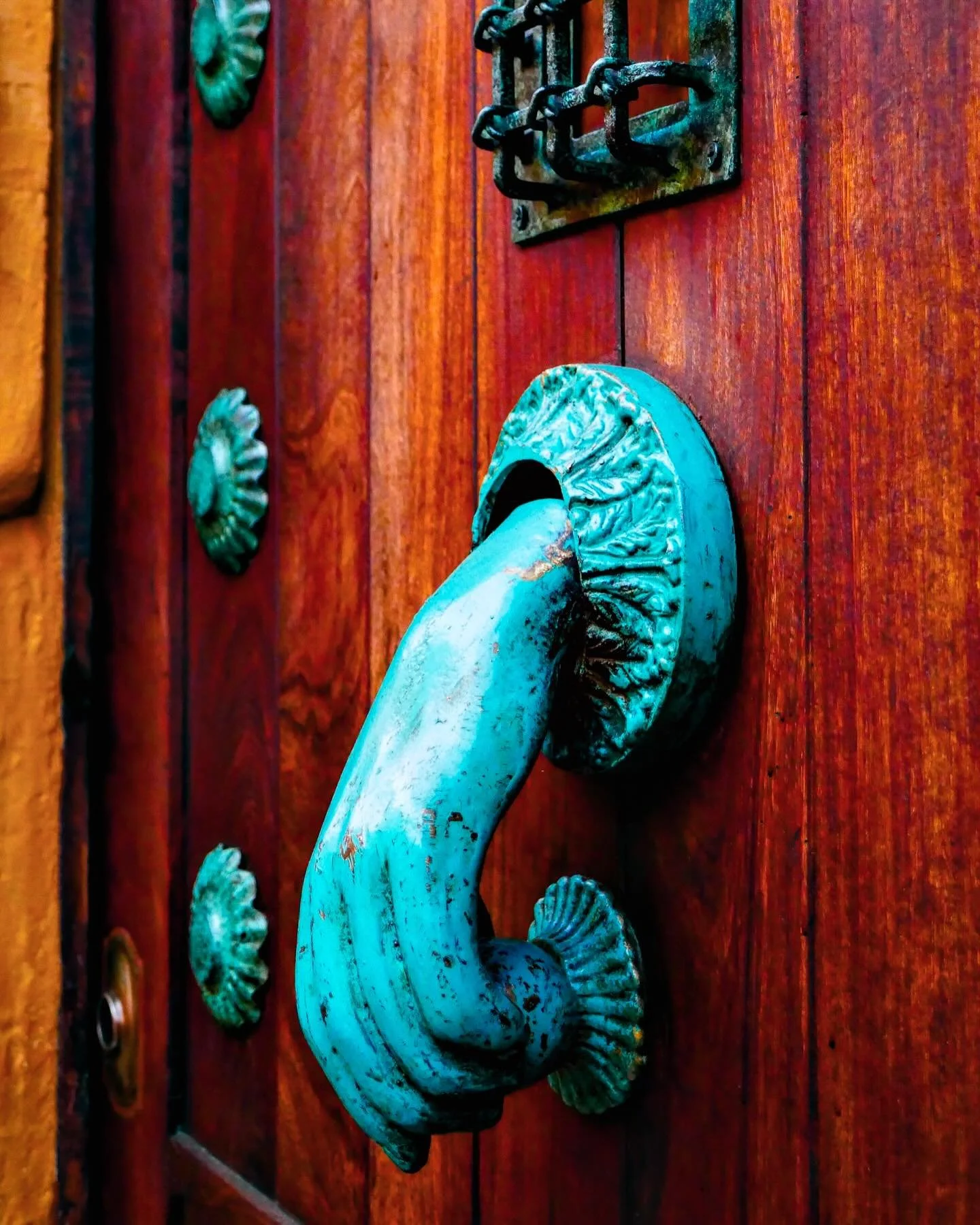 &ldquo;Hamsa&rdquo; &copy; 2025 Skip Hunt

A bright turquoise door knocker shaped like a hand adds a striking contrast to the rich wooden door. Ornamental floral designs and a small metal grate adorn the surface, enhancing its rustic appeal.

San Mig