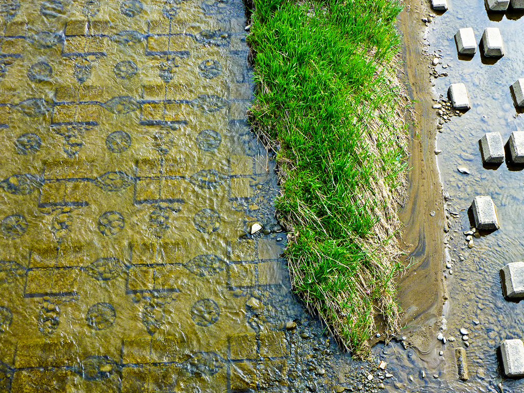 Looking over the bridge railing at the tiling in the river