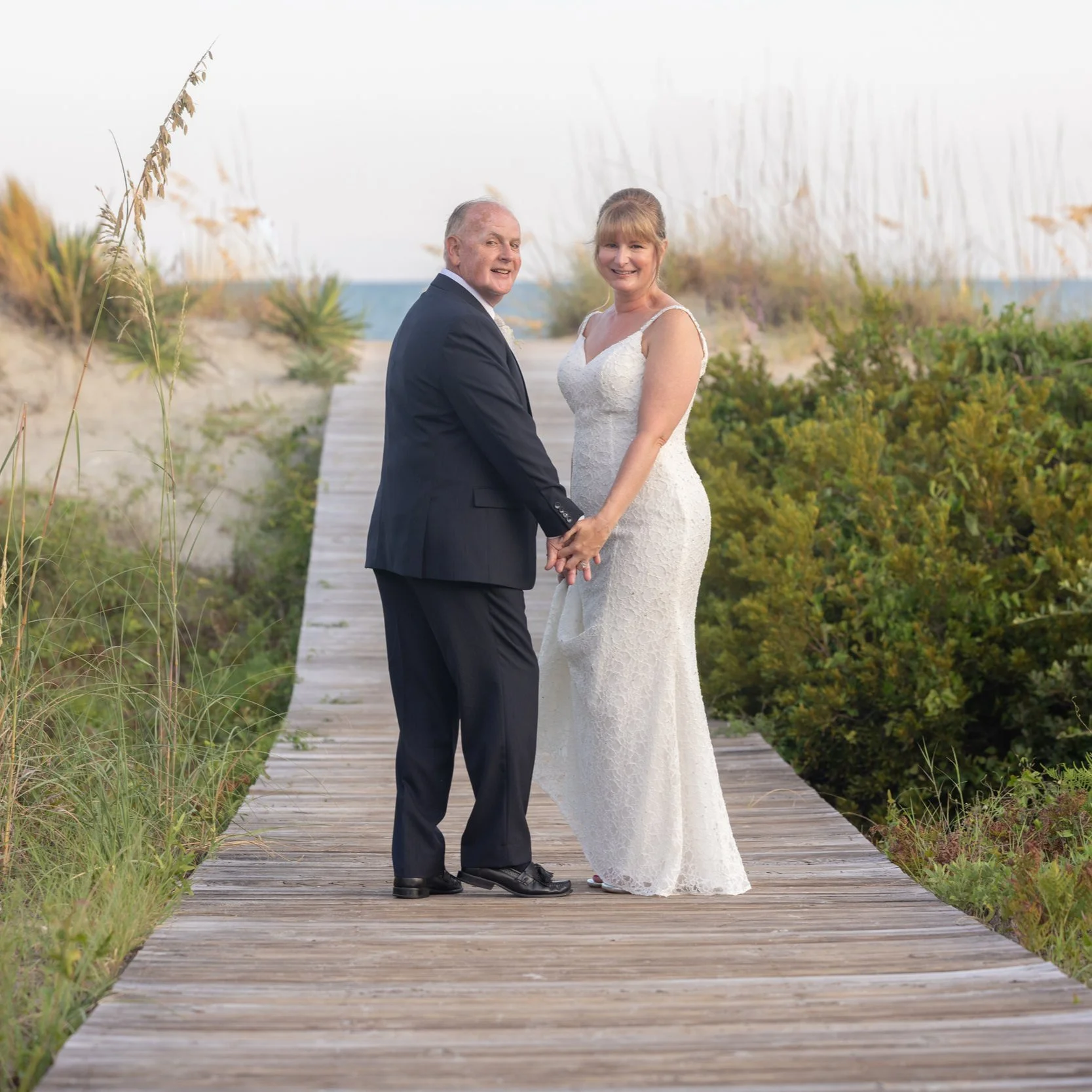 bride and groom pause to smile on the boardwalk