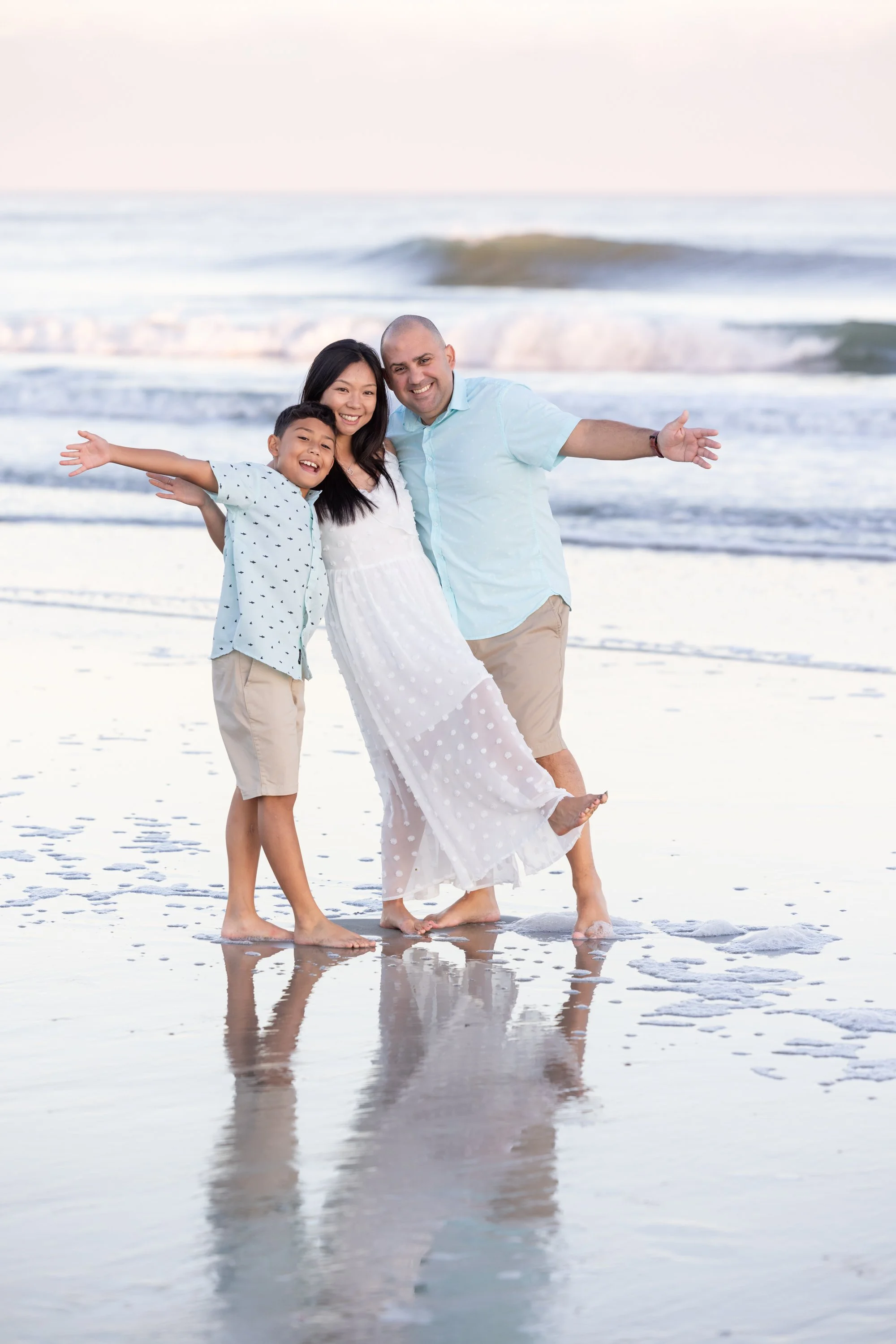 family of three hamming it up at the beach