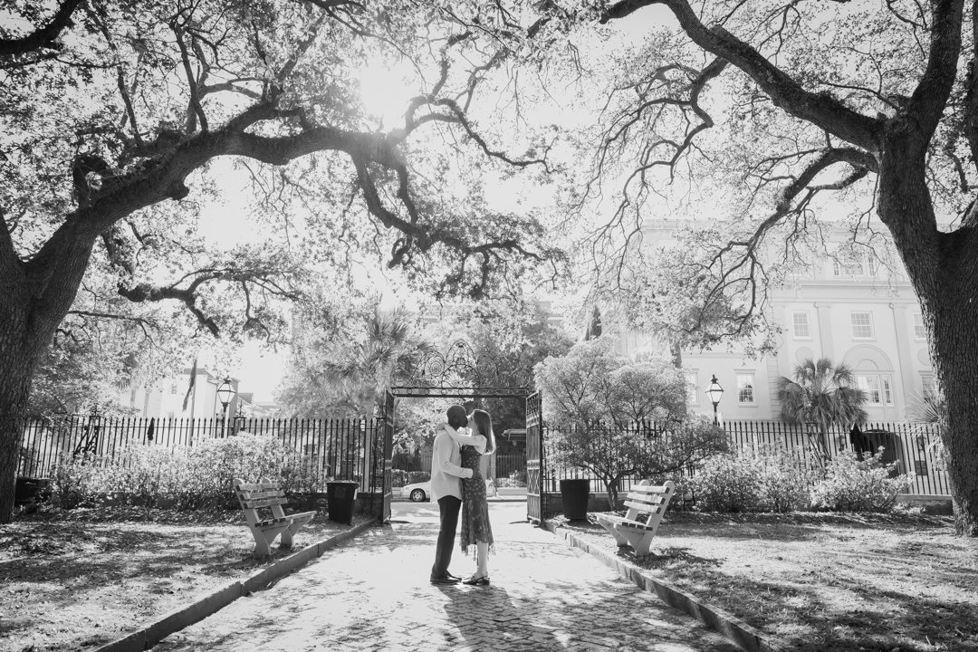 couple kissing under oaks during engagement photos