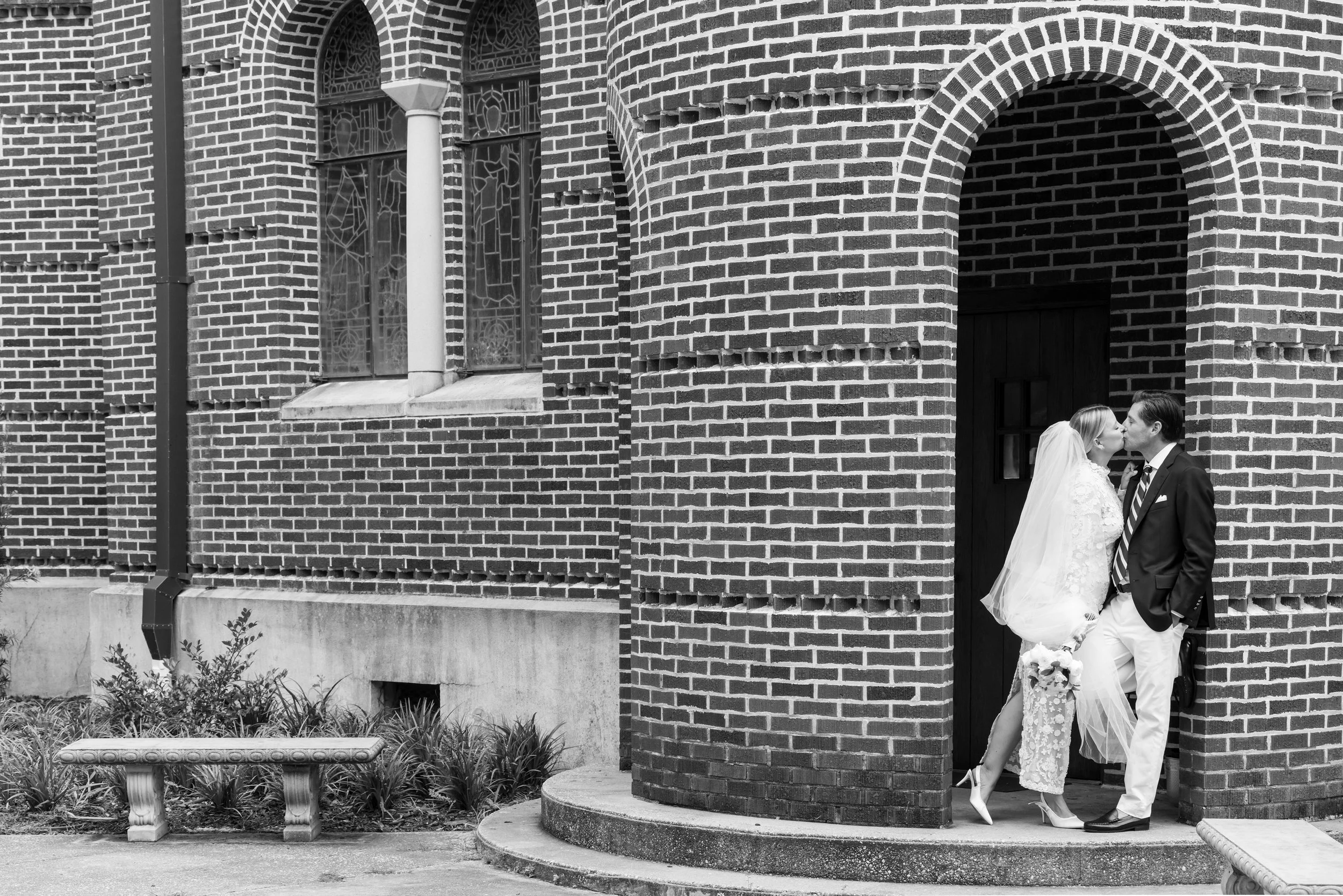 black and white of kissing couple in brick entrywary