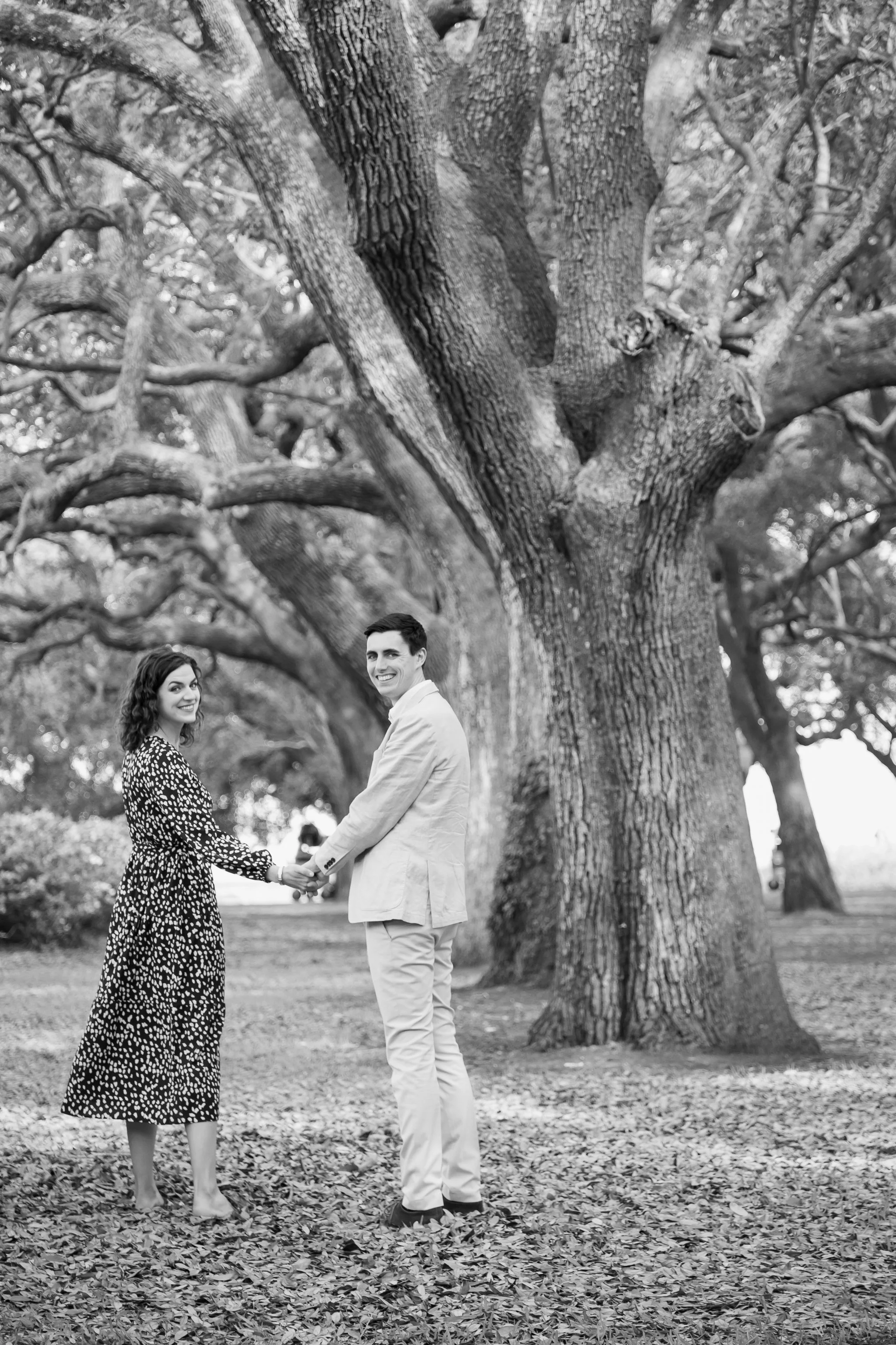 black and white of engaged couple under live oaks